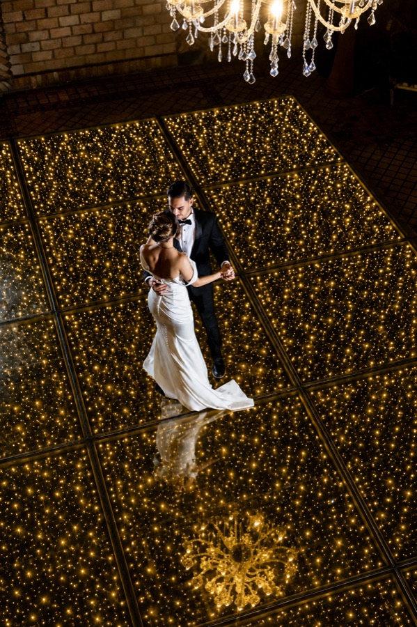 Casal dançando na pista iluminada, visto do alto